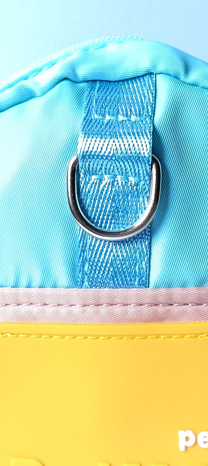 Close-up of the light blue backpack for dogs, showing the silver D-ring detail on the strap, part of our durable dog clothes and dog outfits range.