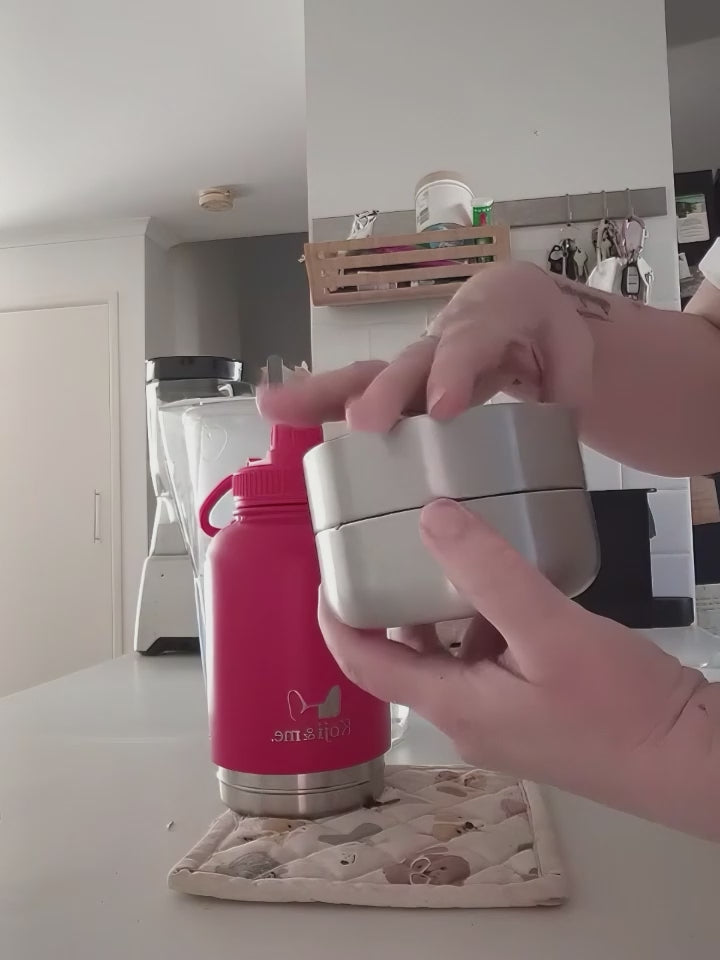Load video: Demonstration video of the red Get-About water bottle, showing screwing off the two stainless steel bowls, filling bowls with treats, and screwing back on to the bottle. Video shows the bottle being filled with water through the wide mouth top.