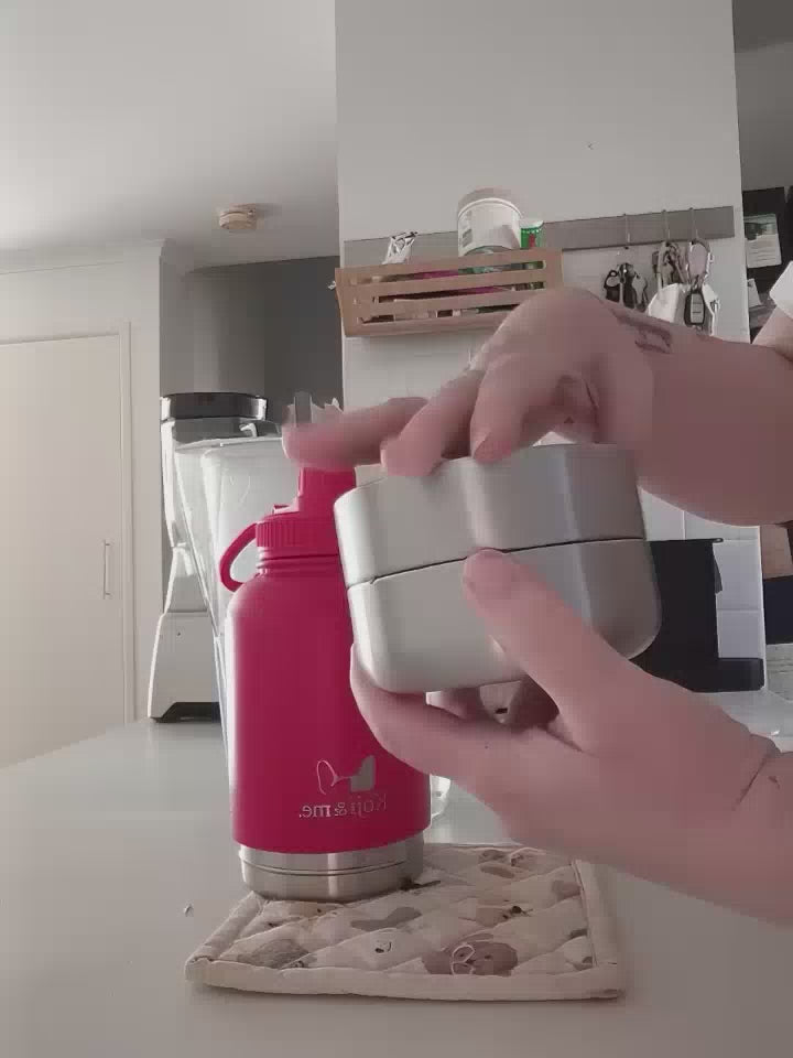 Load video: Demonstration video of the red Get-About water bottle, showing screwing off the two stainless steel bowls, filling bowls with treats, and screwing back on to the bottle. Video shows the bottle being filled with water through the wide mouth top.